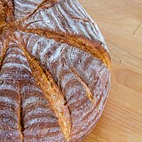Das kräftig ausgebackene Abfrisch-Brot mit leicht bemehlter, röscher Kruste liegt auf einem Holztisch.