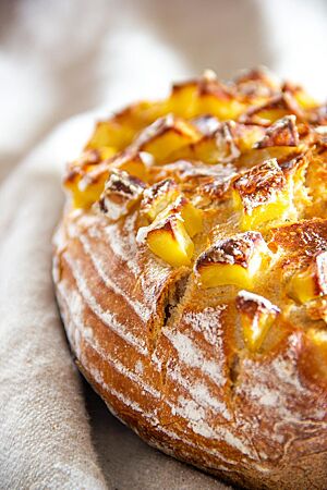 Das rustikale Kartoffelbrot hat eine goldbraun ausgebackene, leicht bemehlte Kruste mit Kartoffelwürfeln auf der Oberseite, die während des Backens kräftig geröstet wurden.