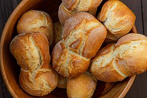 Schlesische Semmel (Breslauer Semmel). In einem Brotkorb liegen mehrere kräftig ausgebackene Schlesische Semmeln in Form von Doppelbrötchen.
