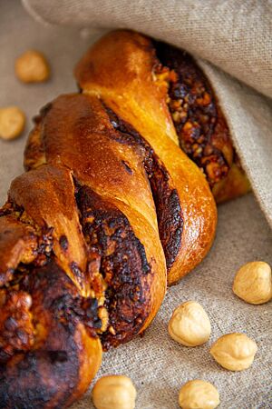 Die aus zwei Teigsträngen geformte, verdrehte und mit Schokolade und Nüssen gefüllte Haselnuss-Schraube liegt kräftig ausgebacken auf einem Leinentuch.