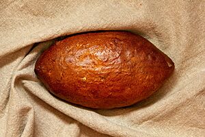 Apfelbrot. Das kräftig ausgebackene Apfelbrot mit glänzender Kruste liegt in einem Leinentuch.