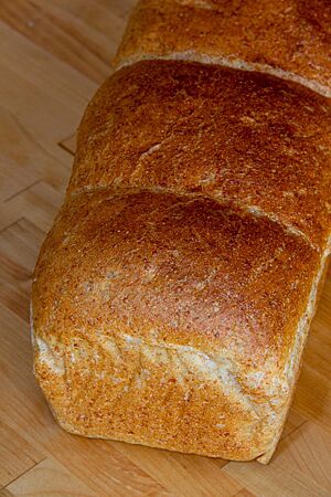 Pain de Mie. Das goldgelb ausgebackene Pain de Mie in Form eines Kastenbrotes hat eine glatte, leicht glänzende Oberfläche.