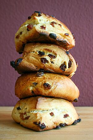 Vier Rosinen-Scones mit Rosinen auf und in der Kruste liegen übereinandergestapelt auf einem Holztisch.