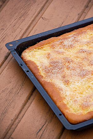 Sächsischer Zuckerkuchen. Der dünne, goldgelb bis goldbraun ausgebackene Zuckerkuchen liegt in einem Kuchenblech.