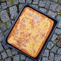 Der sächsische Zuckerkuchen mit karamellisierter Zuckerkruste liegt auf einem dunkelgrauen Steinuntergrund.