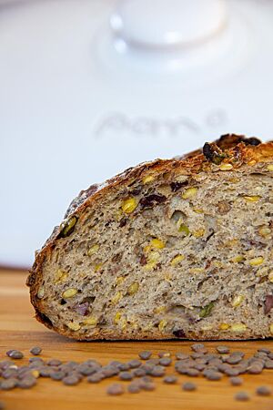 Linsenbrot: wattig-weiche Krume mit einzigartigem Geschmack. Im Anschnitt des Linsenbrotes sind Linsen und Stückchen von saurer Gurke in der weichen, elastischen Krume sichtbar.
