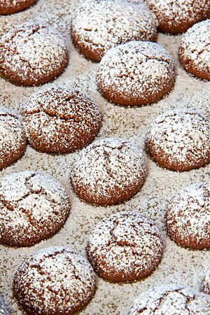 Uroma Ernas Kakaokugeln. Die Oberfläche der gebackenen Schokoladenplätzchen ist in der Mitte leicht aufgebrochen und üppig mit Puderzucker bedeckt.
