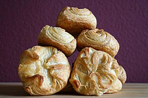 Kieler Franzbrötchen. Die goldgelb ausgebackenen Kieler Franzbrötchen liegen zu einer Pyramide gestapelt auf einem Tisch.
