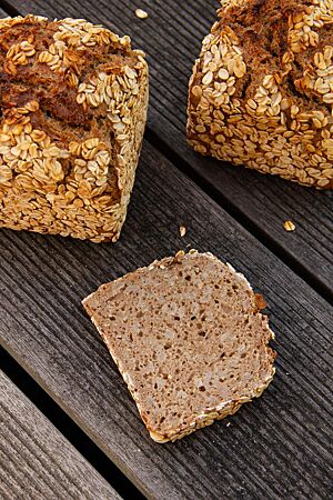 Das kräftig ausgebackene, rustikal aufgerissene Dinkelvollkornmischbrot in Form eines Kastenbrotes ist auf der gesamten Oberfläche mit Haferflocken bestreut.