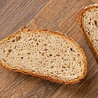 Eine Scheibe des Alles-muss-weg-Brotes zeigt die saftige, kleinporige und lockere Krume.