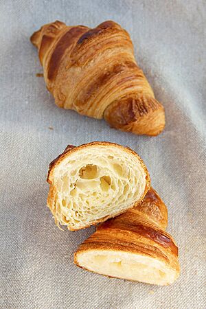 Ein durchgeschnittenes Croissant zeigt die hellgelbe Krume mit mittlerer Porung.