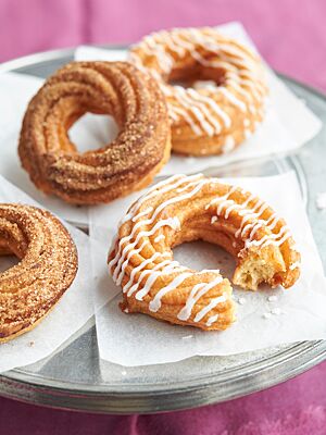 Die aus Brandteig hergestellten, ringförmigen Spritzenkuchen wurden in Zimtzucker gewälzt oder mit Zuckerguss verziert.