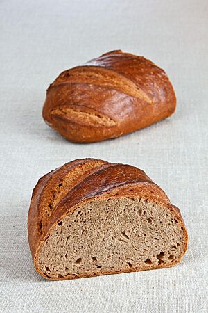 Das halbierte Weizenmischbrot mit goldbraun ausgebackener, glänzender Kruste zeigt die kleinporige Krume mit einzelnen mittleren Poren.