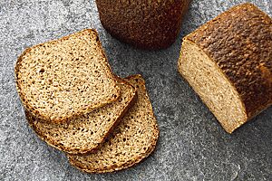 Drei Scheiben des Weizenschrotbrotes in der Sauerteigvariante zeigen die lockere, kleinporige Krume und die kräftig ausgebackene, leicht bemehlte Kruste.