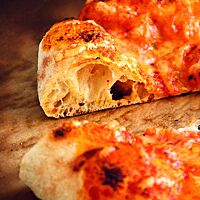 Die angeschnittene Pizza aus Weizenmehl Tipo 3 und Hartweizen zeigt die mittel- bis grobporige Krume und den saftigen Belag.