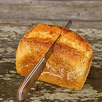 Im goldgelb ausgebackenen Maisbrot steckt ein Brotmesser.
