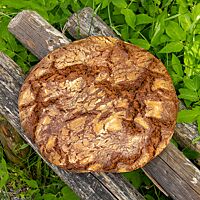Auf einigen verwitterten Holzstangen liegt kräftig ausgebacken der runde Bauernlaib.
