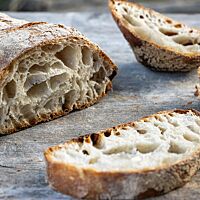 Der angeschnittene Ciabatta-Laib zeigt die ungleichmäßige, offenporige und saftige Krume.