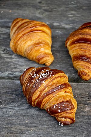 Sauerteigcroissant (2022): mit oder ohne Lauge ein Genuss. Goldbraun ausgebackene Croissants liegen auf einem rustikalen Holztisch.