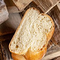 Ansgeschnitten zeigt der Sauerteigzopf die kleinporige, helle Krume unter der dünnen, glänzenden Kruste.