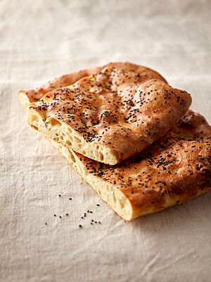 Das fluffige Weizenfladenbrot ist auf der Kruste mit schwarzem Sesam bestreut und kräftig ausgebacken.