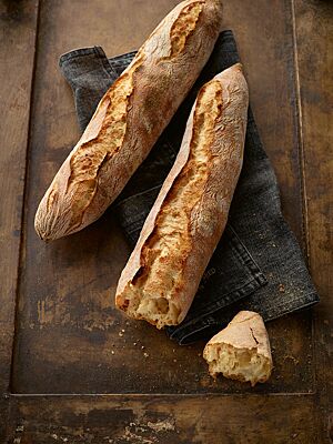 Die zwei rustikal aufgerissenen Baguettes haben eine knusprig-krachende Kruste und eine grobporige Krume.