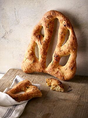 Die Fougasse hat eine goldgelb bis goldbraun ausgebackene Kruste, die mit Rosmarinnadeln und grobem Salz bestreut ist.