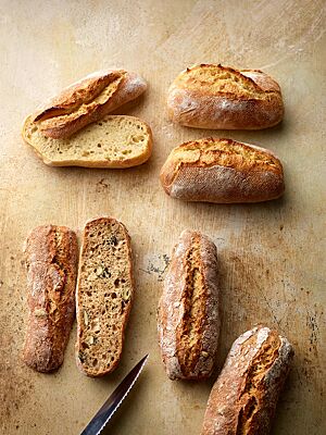 Die Dinkelbrötchen (oben) und die Körnerbrötchen (unten) sind jeweils länglich geformt als auch kräftig ausgebacken und haben eine kleinporige, saftige Krume, wobei die Körnerbrötchen zusätzlich Saaten beinhalten.