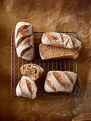 Die eckigen Dinkelvollkornbrötchen (rechts) und Weizenvollkornbrötchen (links) haben eine bemehlte, mehrfach diagonal eingeschnittene Kruste und eine kleinporige, dunkle Krume.