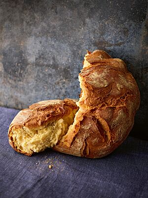 Die kräftig ausgebackene, rustikal aufgerissene Brioche mit dicker, leicht bemehlter Kruste hat eine goldgelbe, mittelporige Krume.