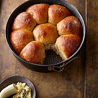 In einer Springform liegen dicht aneinandergebacken mehrere goldbraune Brötchen mit weicher, saftiger Krume.