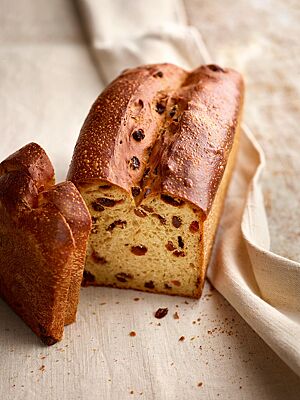 Das in einer Kastenform gebackene Rosinenbrot mit glänzender, goldbraun ausgebackener Kruste zeigt im Anschnitt seine hellgelbe, kleinporige und großzügig mit Rosinen bestückte Krume.