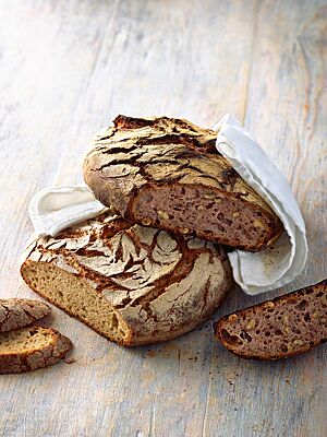Sowohl das Schmalzbrot mit heller, kleinporiger Krume (unten) als auch das Nussbrot mit rötlich-violett gefärbter, lockerer Krume (oben) haben eine kräftig ausgebackene, rustikal aufgerissene und bemehlte Kruste.