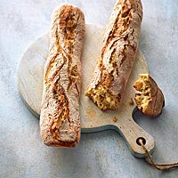 Die Dinkelstangen in Form von Baguettes haben eine lockere, elastische Krume mit wilder Porung und eine knusprige, rustikal aufgerissene Kruste.