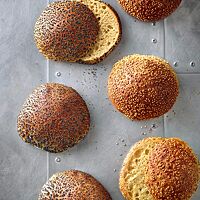 Die mit Mohn bestreuten Hamburgerbrötchen mit Vollkornanteil (links) und die mit Sesam bestreuten Hamburgerbrötchen aus hellem Mehl (rechts) haben eine goldbraun ausgebackene Kruste und eine goldgelbe, lockere Krume.