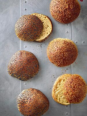 Die mit Mohn bestreuten Hamburgerbrötchen mit Vollkornanteil (links) und die mit Sesam bestreuten Hamburgerbrötchen aus hellem Mehl (rechts) haben eine goldbraun ausgebackene Kruste und eine goldgelbe, lockere Krume.