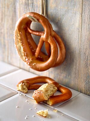 Die Laugenbrezeln mit glänzender Oberfläche und dünnen Ärmchen sind am Bauch eingeschnitten und mit grobem Salz bestreut.