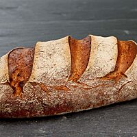 Das Weizenmischbrot hat eine kräftig ausgebackene, bemehlte Kruste mit drei schräg gesetzten Einschnitten.