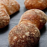 Die paarweise aneinandergebackenen Schweizer Weizenbrötchen haben eine kräftig ausgebackene, dünne Kruste mit glatter Oberfläche.