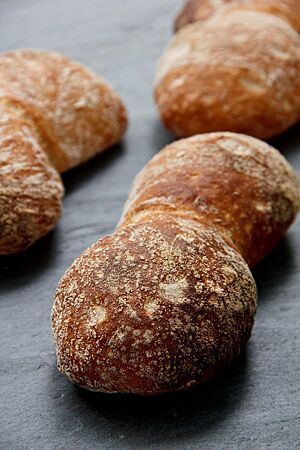 Die paarweise aneinandergebackenen Schweizer Weizenbrötchen haben eine kräftig ausgebackene, dünne Kruste mit glatter Oberfläche.