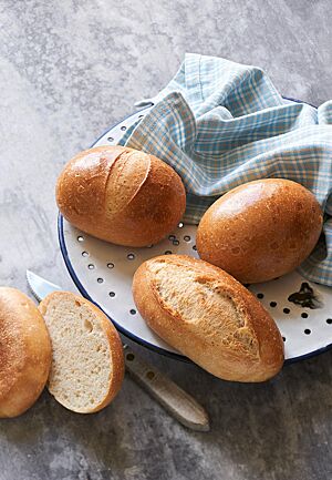 Das goldbraun ausgebackene Rheinische Schnittbrötchen mit glänzender, eingeschnittener und rustikal aufgerissener Kruste (unten) liegt neben zwei Hamburger Rundstücken.