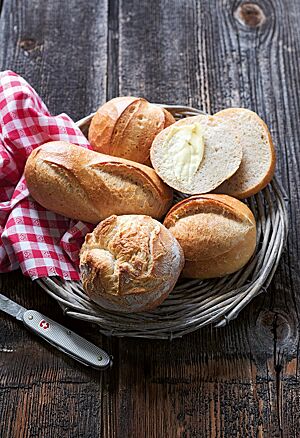 Ein goldbraun ausgebackenes Pariserli mit baguetteähnlichen Einschnitten (links) liegt neben einem Schlumbergerli (unten), einem Mütschli (oben) sowie einem Glarner Brötli (rechts) in einem geflochtenem Brotkorb.
