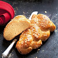 Der angeschnittene Schweizer Dinkelzopf hat eine goldbraun ausgebackene, feine Kruste die mit Mandelblättchen bestreut ist. Die kleinporige Krume ist elastisch und faserig.