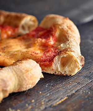 Im Anschnitt zeigt die mit Tomatensauce und Mozzarella belegte Pizza den knusprig ausgebackenen Rand mit der grobporige Krume.