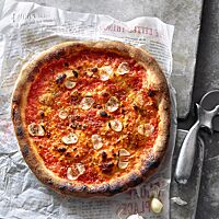 Die Pizza Marinara ist mit Tomatensauce, Knoblauch und Oregano belegt und hat einen dunkel ausgebackenen, knusprigen Rand.