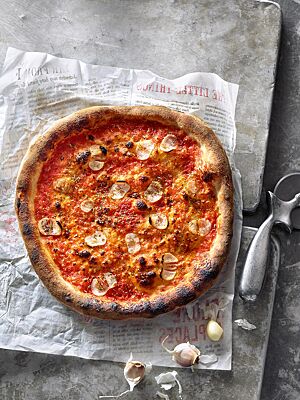 Die Pizza Marinara ist mit Tomatensauce, Knoblauch und Oregano belegt und hat einen dunkel ausgebackenen, knusprigen Rand.