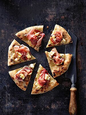 Eine kräftig ausgebackene, in sechs Teile geschnittene Pizza Gorgonzola ist mit Mozzarella, Prosciutto, Feigen und Gorgonzola belegt sowie mit Balsamicocreme und Honig beträufelt.