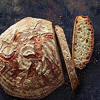Das Pizzabrot hat eine kräftig ausgebackene, rustikal aufgerissene Kruste mit ringförmigen Mehlspuren auf der Oberfläche und eine lockere, mittelporige Krume.