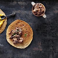 Das Injeera-Fladenbrot mit Linsen-Wot (links) und das Injeera mit Rindfleisch-Wot (rechts) sind sehr dünn, wurden goldbraun ausgebacken und haben eine schwammige, pfannkuchenartige Oberfläche.