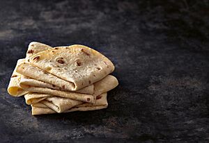 Zu Vierteln gelegte Tortilla-Fladen mit heller Kruste und einigen dunklen Stellen liegen gestapelt aufeinander.